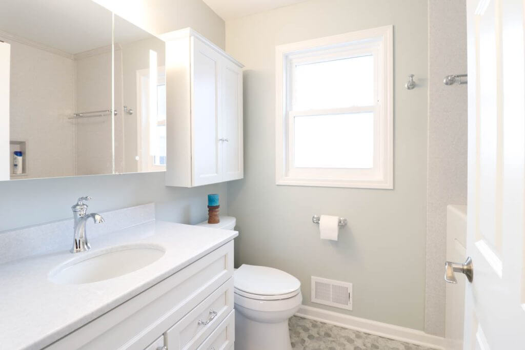 completed bathroom remodel by Odd Fellows Contracting in Williamston, MI with white vanity and hex tile flooring