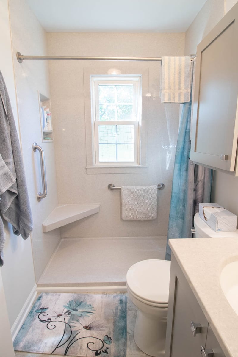 accessible shower detail from bathroom remodel by Odd Fellows Contracting in Mulliken, MI showcasing safety grab bar and molded bench