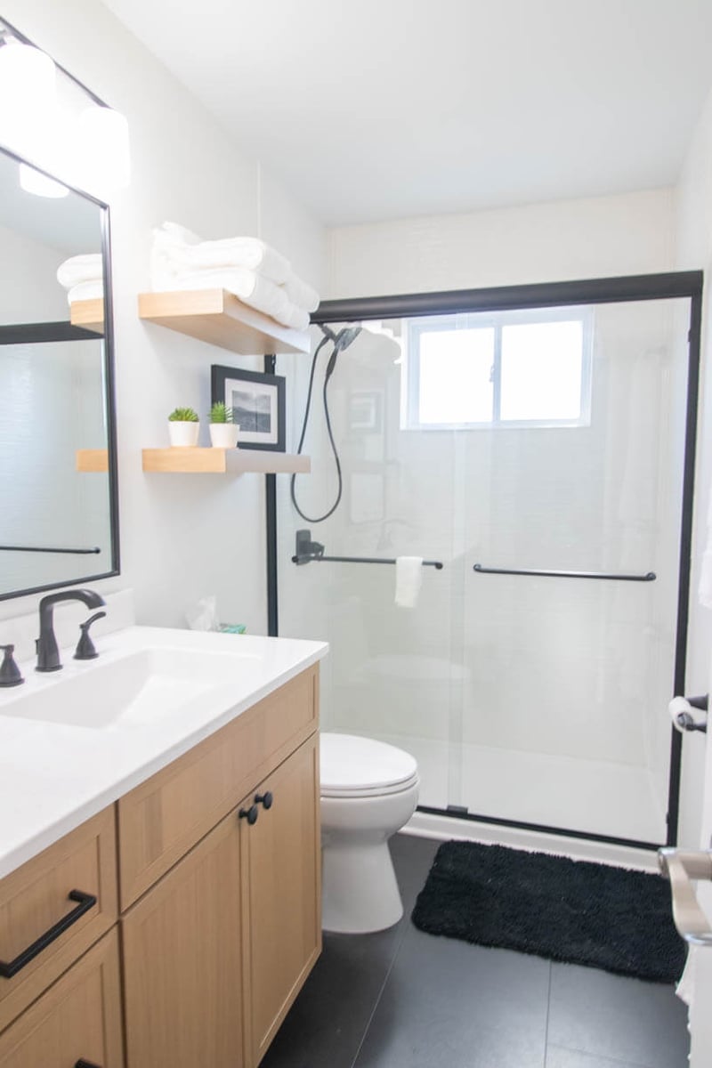 modern bathroom remodel by Odd Fellows Contracting in Holt, MI with wood vanity and black fixtures