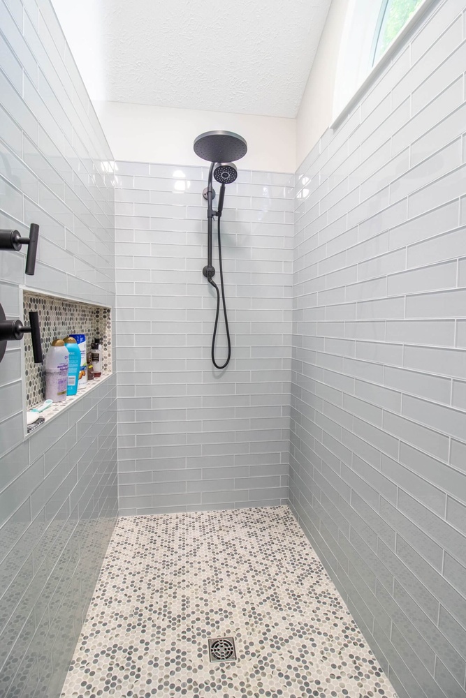 walk-in shower from bathroom remodel by Odd Fellows Contracting in Portland, MI with gray subway tile and pebble floor