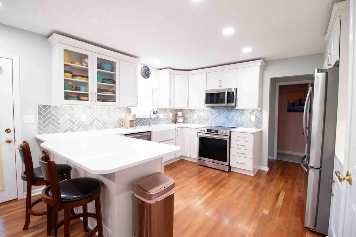 Kitchen remodel with white cabinetry and quartz island by Odd Fellows Contracting in Williamston, MI