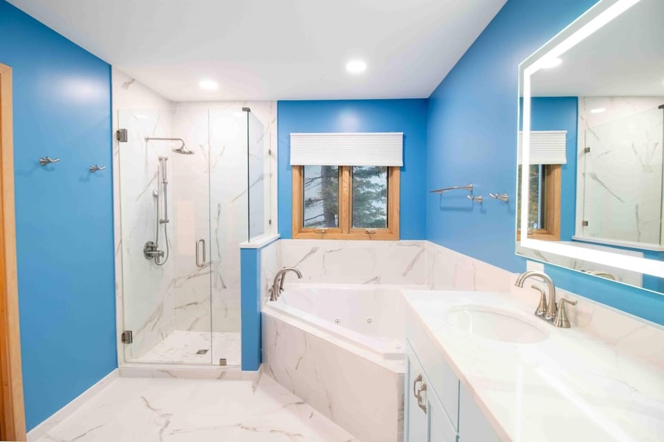 remodeled bathroom toilet area with blue accent walls and marble look tile flooring by Odd Fellows Contracting in Okemos MI