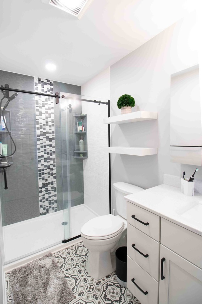 remodeled bathroom with modern vanity cabinet patterned tile flooring and glass shower by Odd Fellows Contracting in Okemos MI