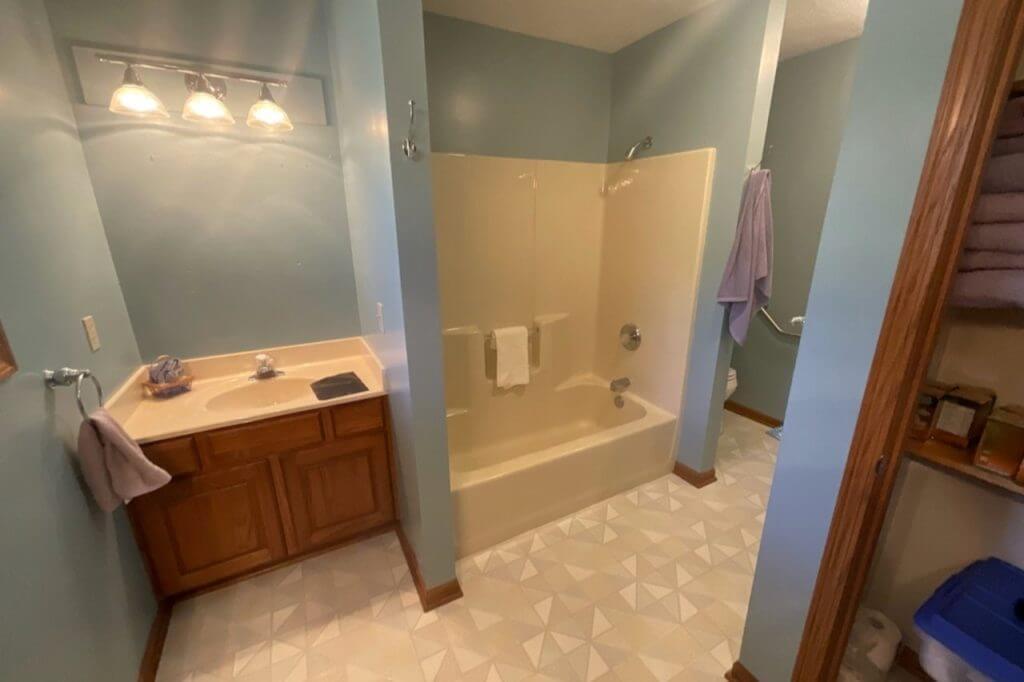 before bathroom remodel with outdated vanity and bathtub by Odd Fellows Contracting in Mason MI