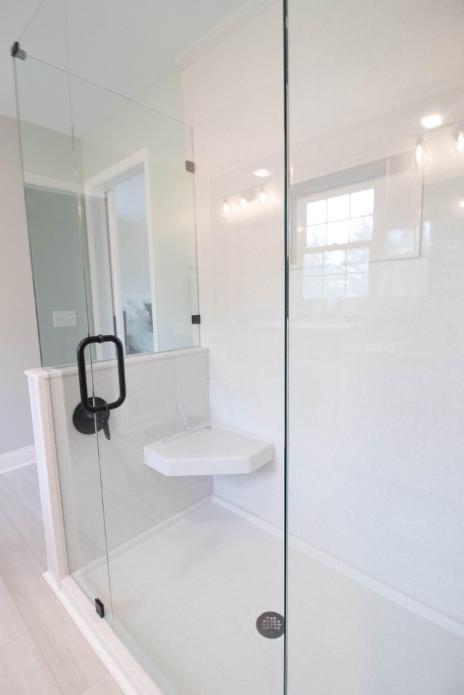 remodeled bathroom shower with frameless glass enclosure and modern fixtures by Odd Fellows Contracting in Holt MI
