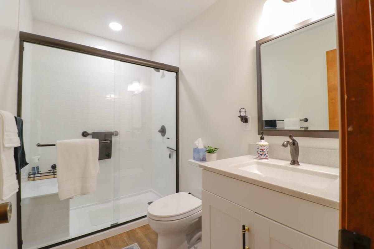 Holt, MI bathroom remodel by Odd Fellows Contracting featuring white cabinetry and glass shower enclosure.