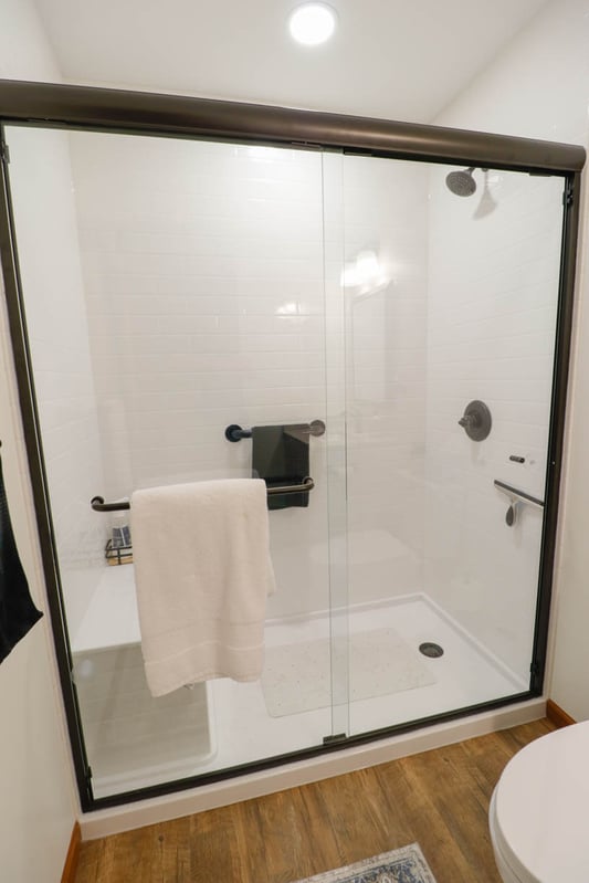 Walk-in shower remodel by Odd Fellows Contracting in Holt, MI with white tile and glass enclosure