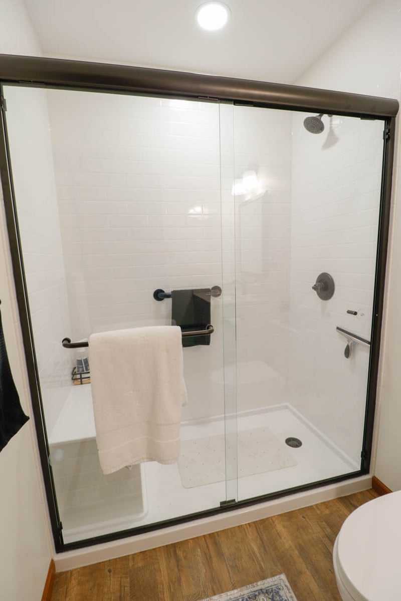 Walk-in shower remodel by Odd Fellows Contracting in Holt, MI with white tile and glass enclosure.