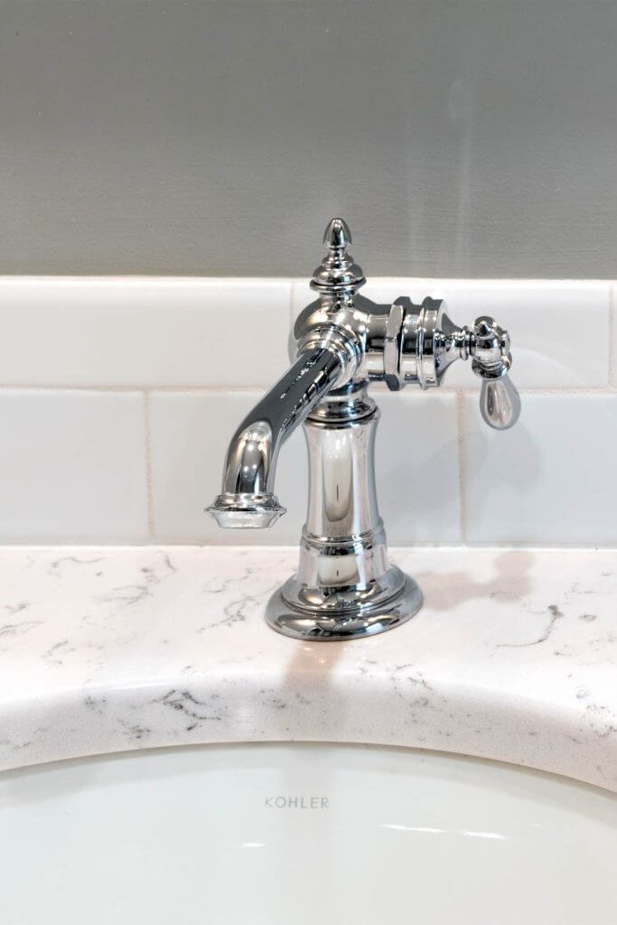 Close-up of bathroom sink faucet and marble countertop in Williamston MI remodel by Odd Fellows Contracting