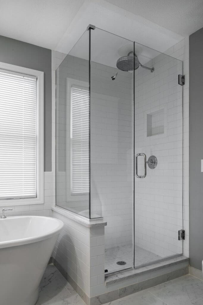 Frameless glass walk-in shower with white tile from master bathroom remodel by Odd Fellows Contracting in Williamston, MI