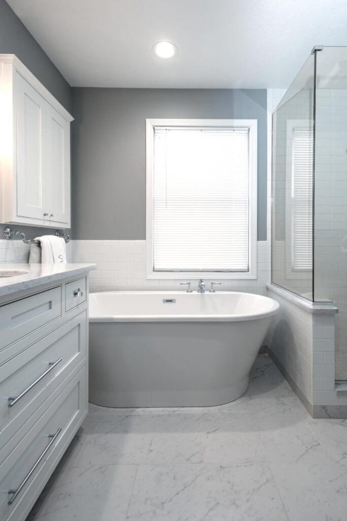 Freestanding bathtub beside custom vanity in master bathroom remodel by Odd Fellows Contracting in Williamston, MI