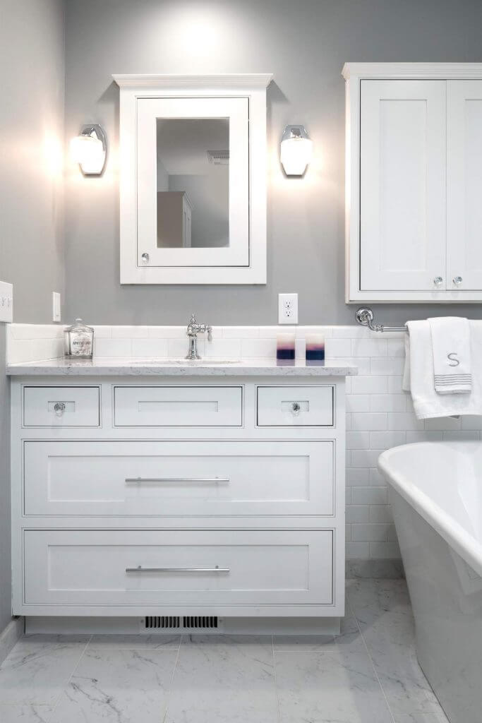 Modern white vanity with subway tile backsplash from a master bathroom remodel by Odd Fellows Contracting in Williamston, MI