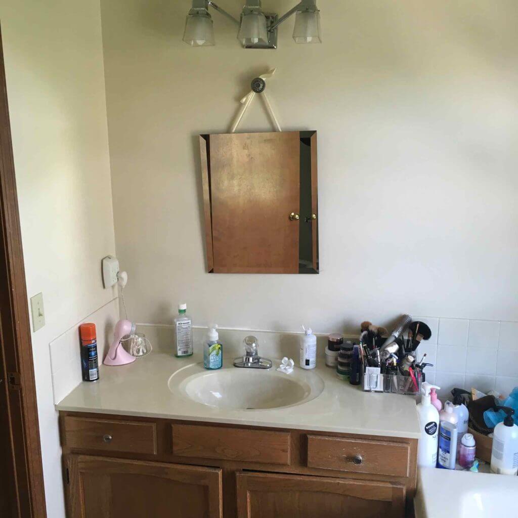 Original bathroom vanity and sink before renovation in a master bathroom remodel by Odd Fellows Contracting in Williamston, MI