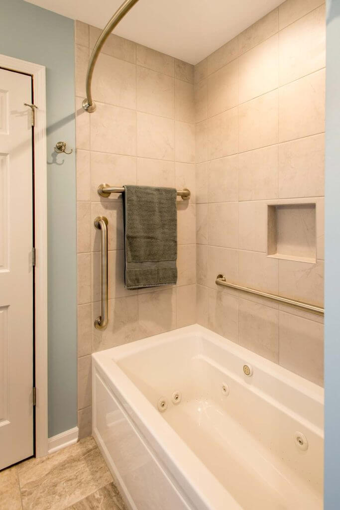 Bathtub with tiled wall surround and grab bars in Holt MI bathroom remodel by Odd Fellows Contracting