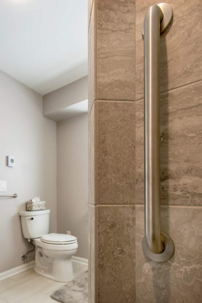 Close-up of shower grab bar and tile wall detail in Holt MI bathroom renovation by Odd Fellows Contracting
