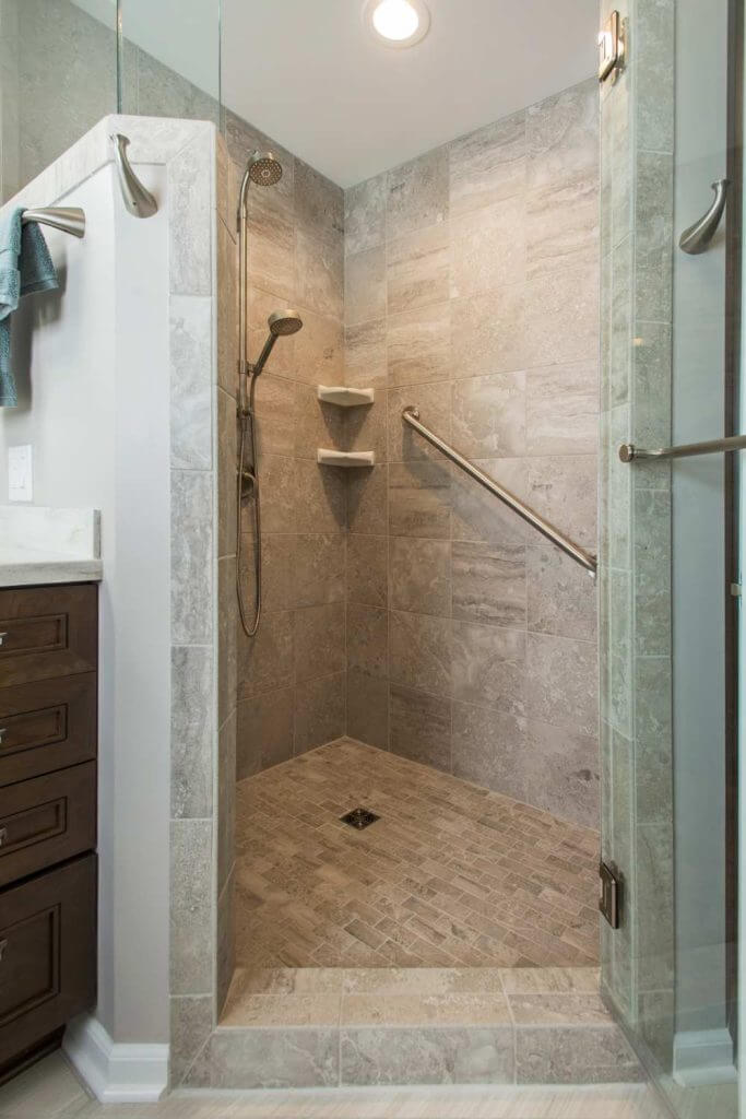 Modern walk-in shower with tile walls and glass enclosure in Holt MI bathroom remodel by Odd Fellows Contracting