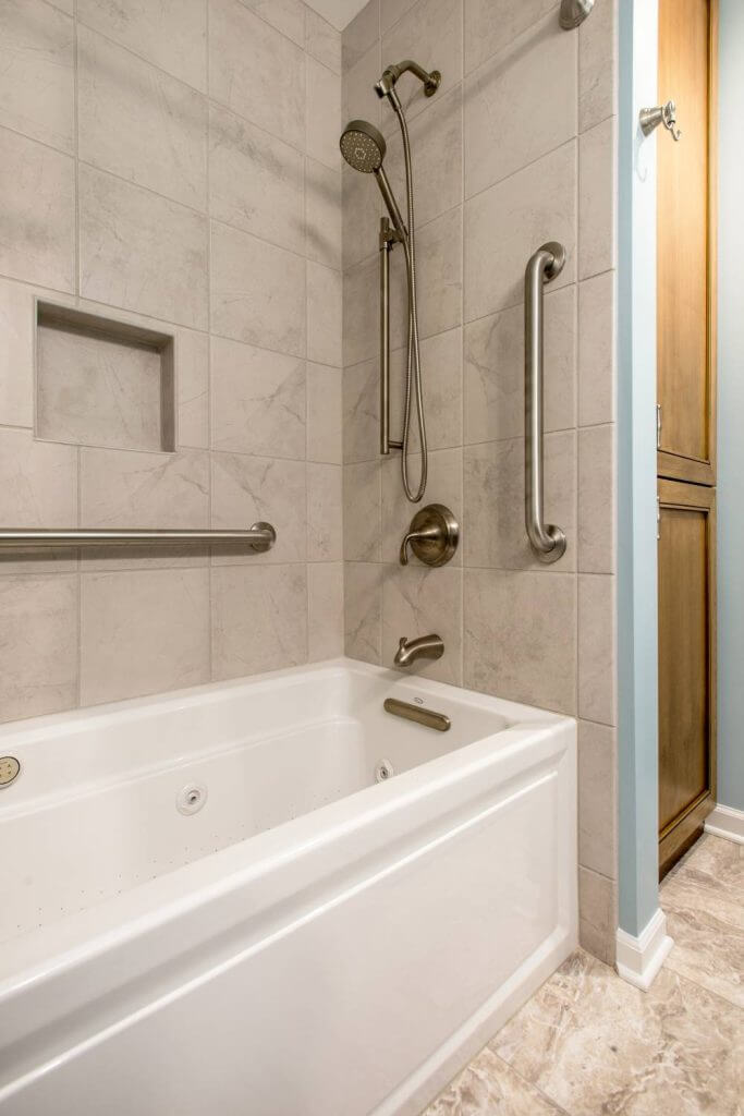 Tiled tub surround with shower head and accessibility bars installed by Odd Fellows Contracting in Holt, MI