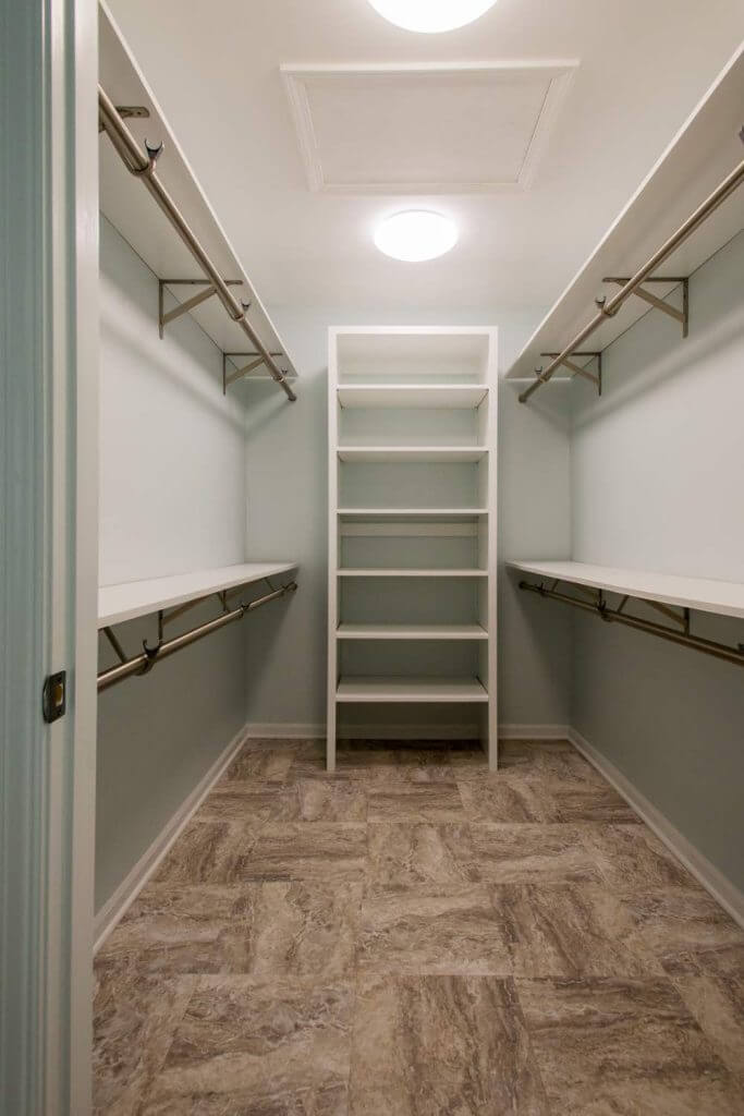 Walk-in closet with shelving and hanging rods from Holt MI bathroom remodel by Odd Fellows Contracting