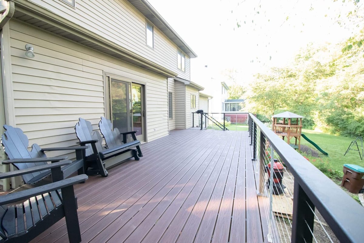 elevated composite deck with railing and seating area by Odd Fellows Contracting in Haslett, MI