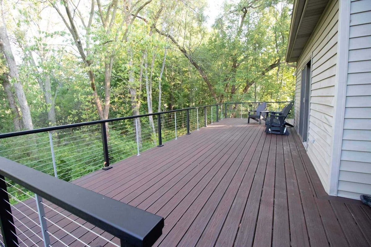 finished composite deck overlooking wooded backyard by Odd Fellows Contracting in Haslett, MI