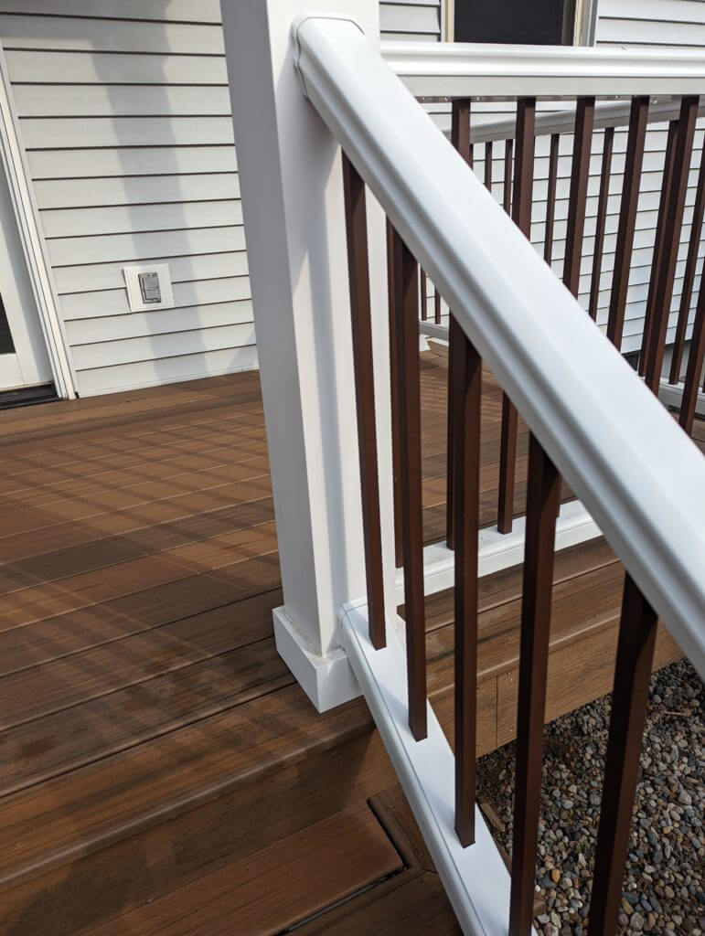 custom deck railing detail with white posts and brown balusters by Odd Fellows Contracting in Lansing, MI