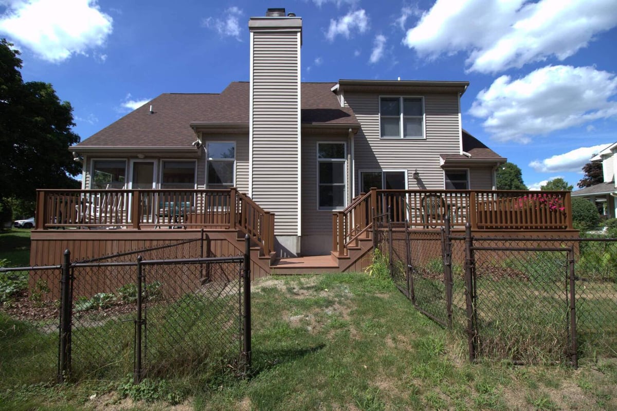 Deck remodel showing new composite stairs connecting upper and lower deck by Odd Fellows Contracting in Haslett, MI