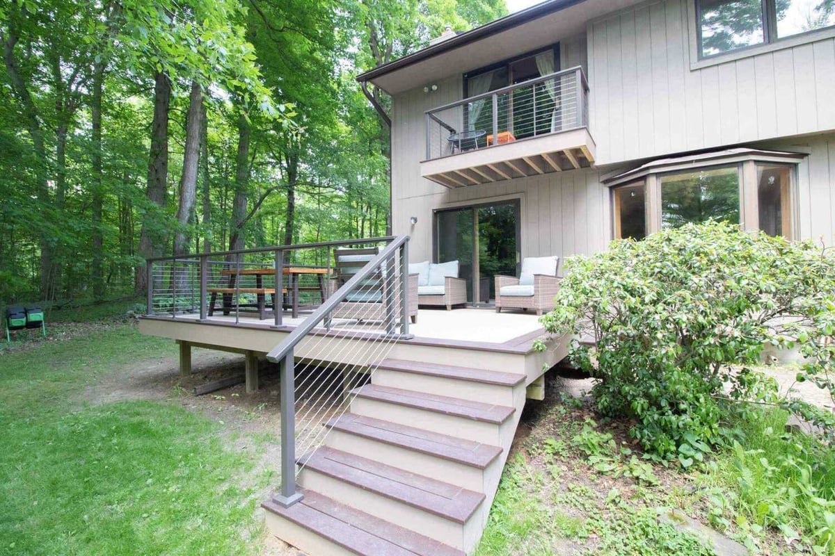 Backyard composite deck and staircase with cable railing from deck remodel by Odd Fellows Contracting in Mason, MI