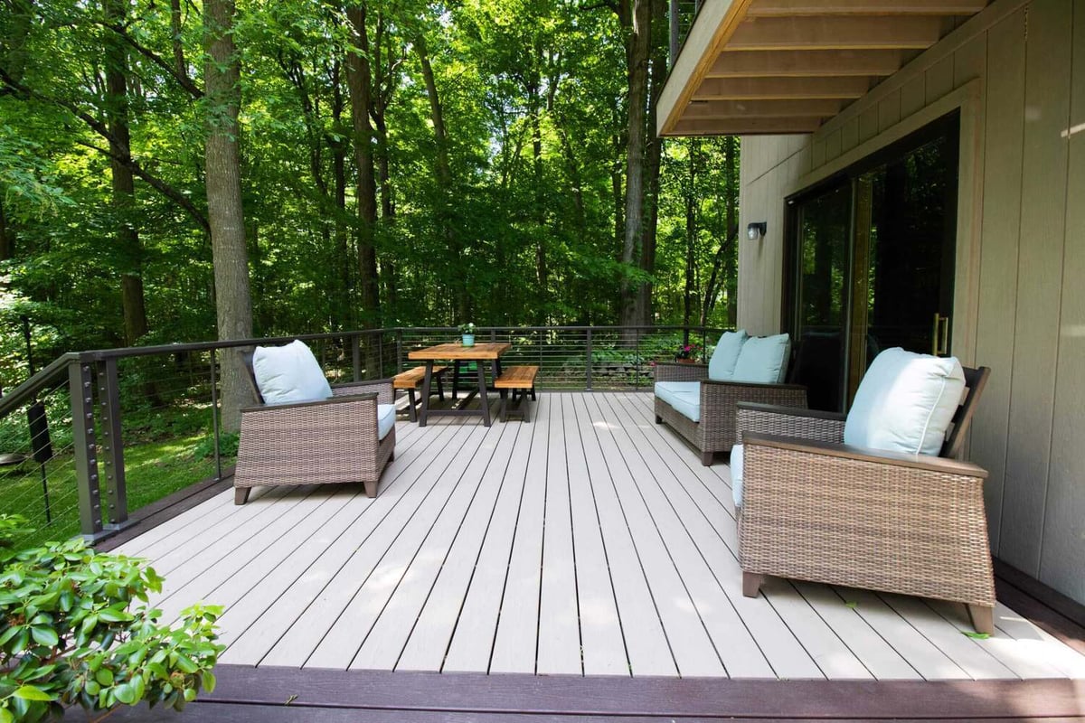 Outdoor living space from deck remodel with dining table and seating by Odd Fellows Contracting in Mason, MI