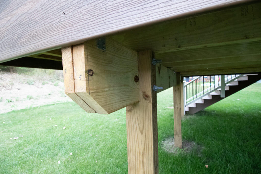 deck framing and support posts underneath elevated deck by Odd Fellows Contracting in Williamston, MI