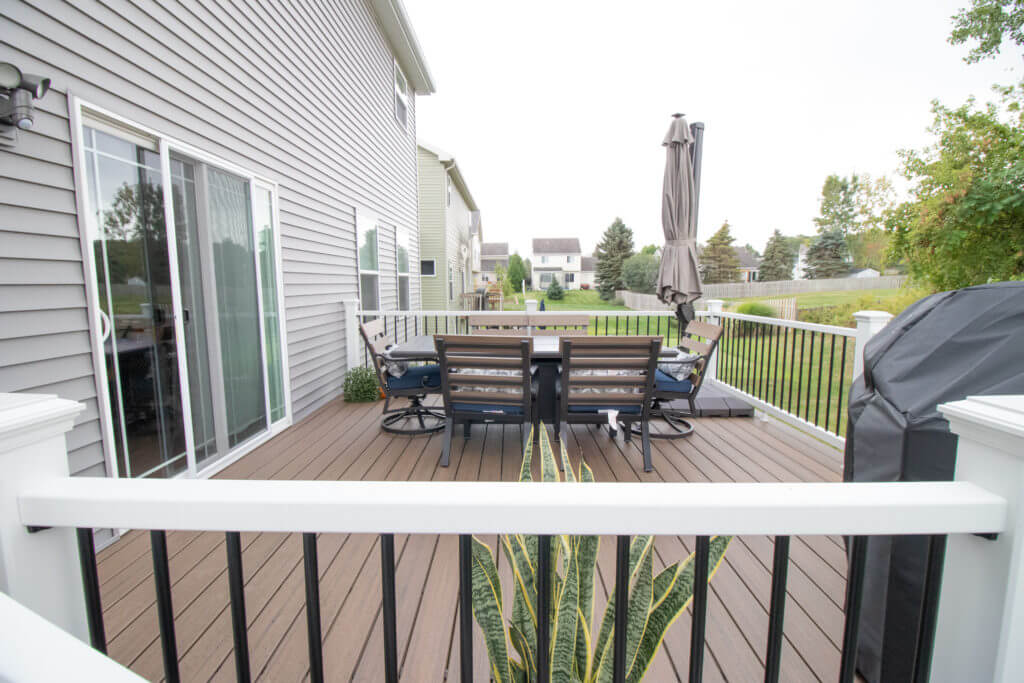 elevated composite deck with outdoor seating and house access by Odd Fellows Contracting in Williamston, MI