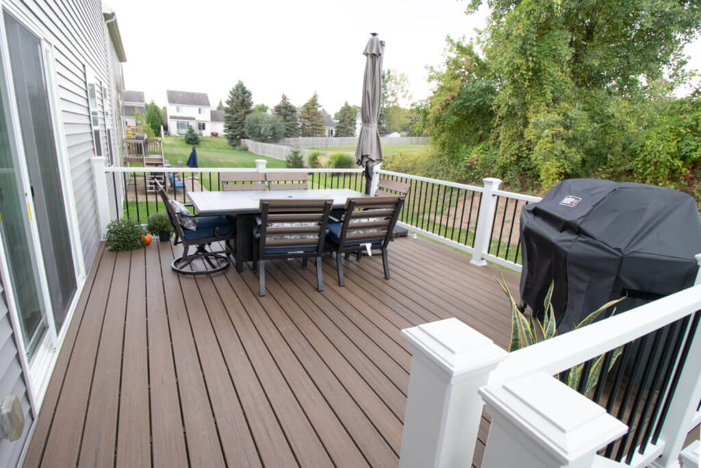 finished composite deck with outdoor dining area and railing by Odd Fellows Contracting in Williamston, MI