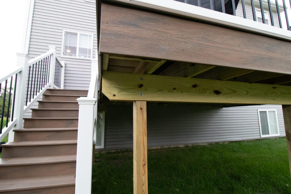 underside structure of elevated deck addition with support posts by Odd Fellows Contracting in Williamston, MI