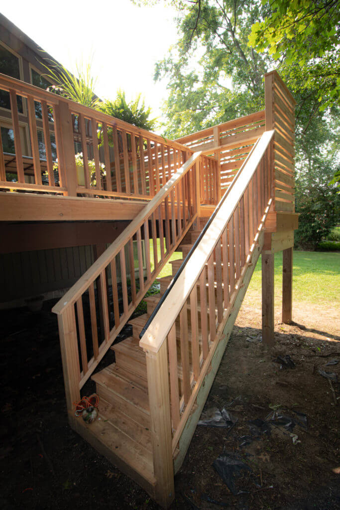 cedar deck stairs with wood railing and privacy wall by Odd Fellows Contracting in Haslett MI