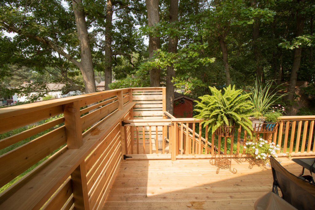 elevated cedar deck with privacy screen and railing by Odd Fellows Contracting in Haslett MI