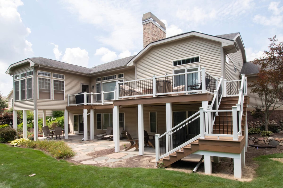 elevated composite deck remodel with white posts and black railing system by Odd Fellows Contracting in Williamston, MI