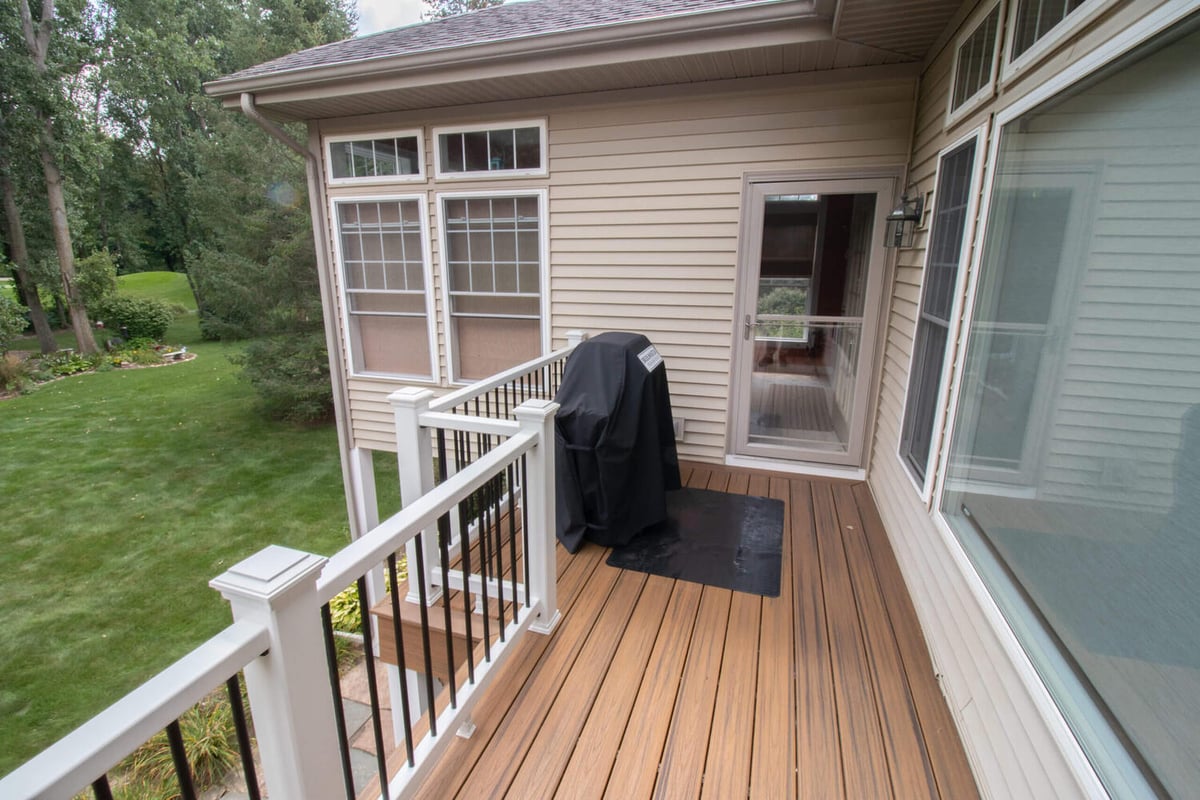 outdoor deck renovation with composite decking and white railing overlooking backyard by Odd Fellows Contracting in Williamston, MI