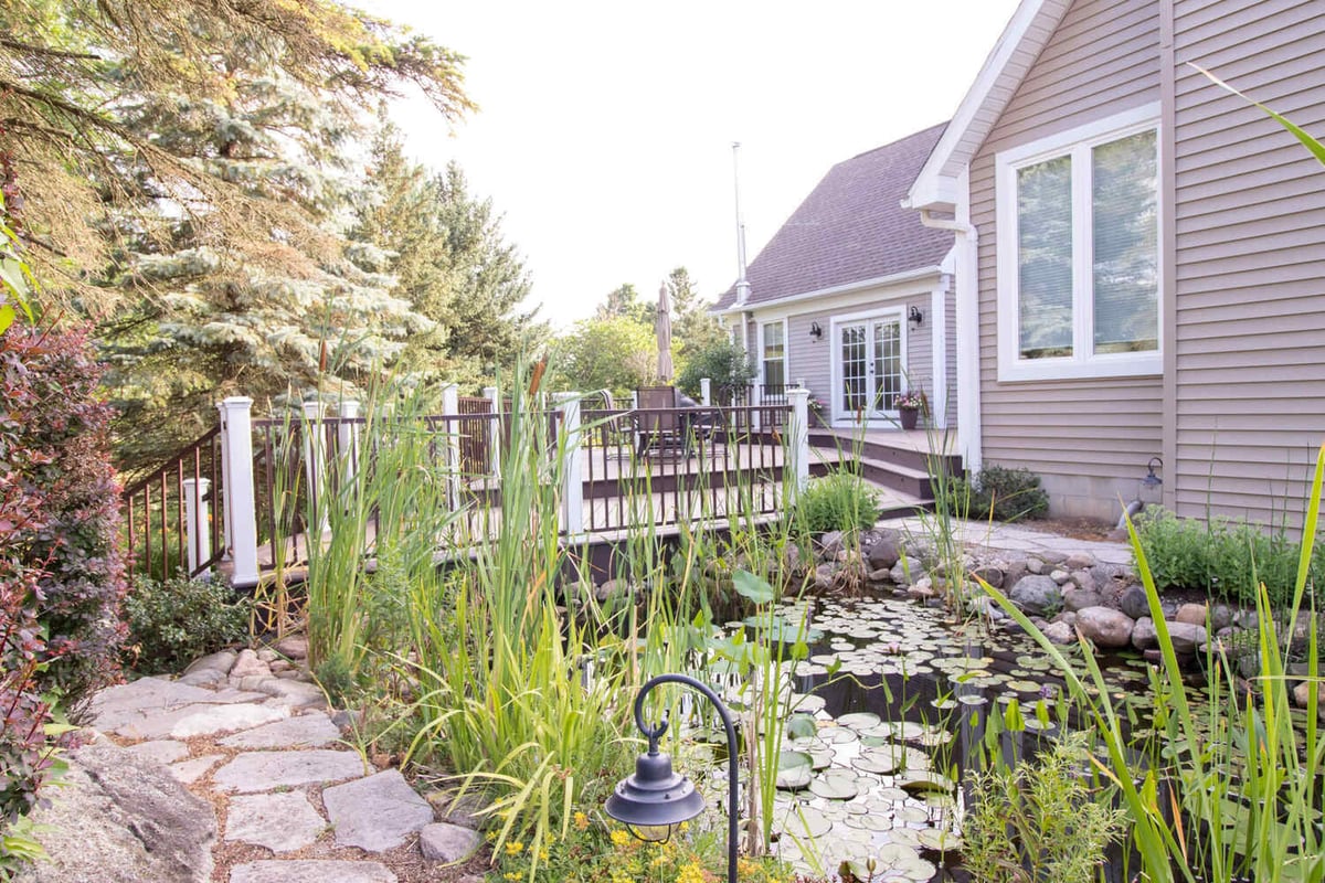 backyard outdoor space by Odd Fellows Contracting in Williamston MI with pond and elevated deck