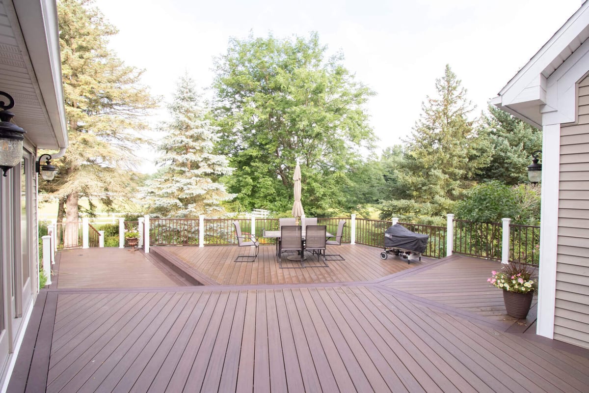 custom deck detail by Odd Fellows Contracting in Williamston MI with brown railing and white columns