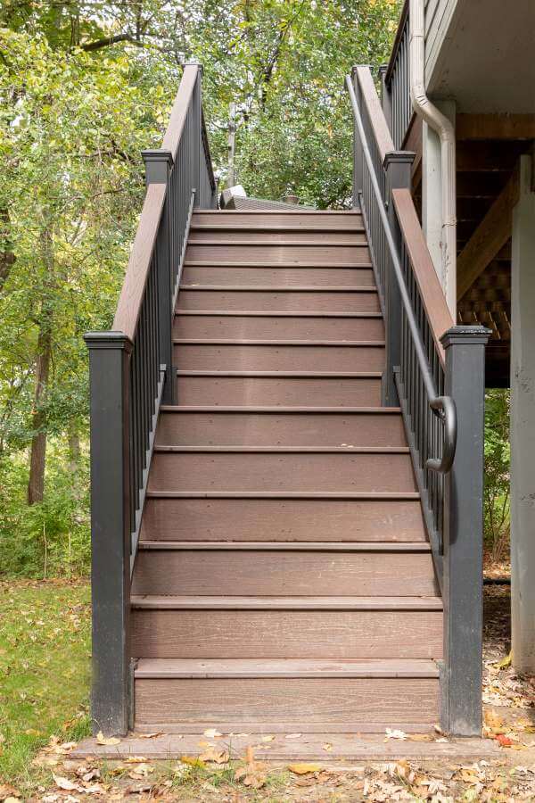 Large composite deck lounge space overlooking wooded backyard by Odd Fellows Contracting in Okemos MI