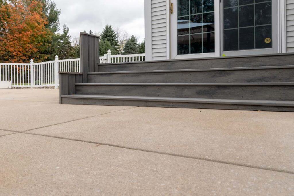 Backyard outdoor living renovation with deck stairs by Odd Fellows Contracting in Williamston MI