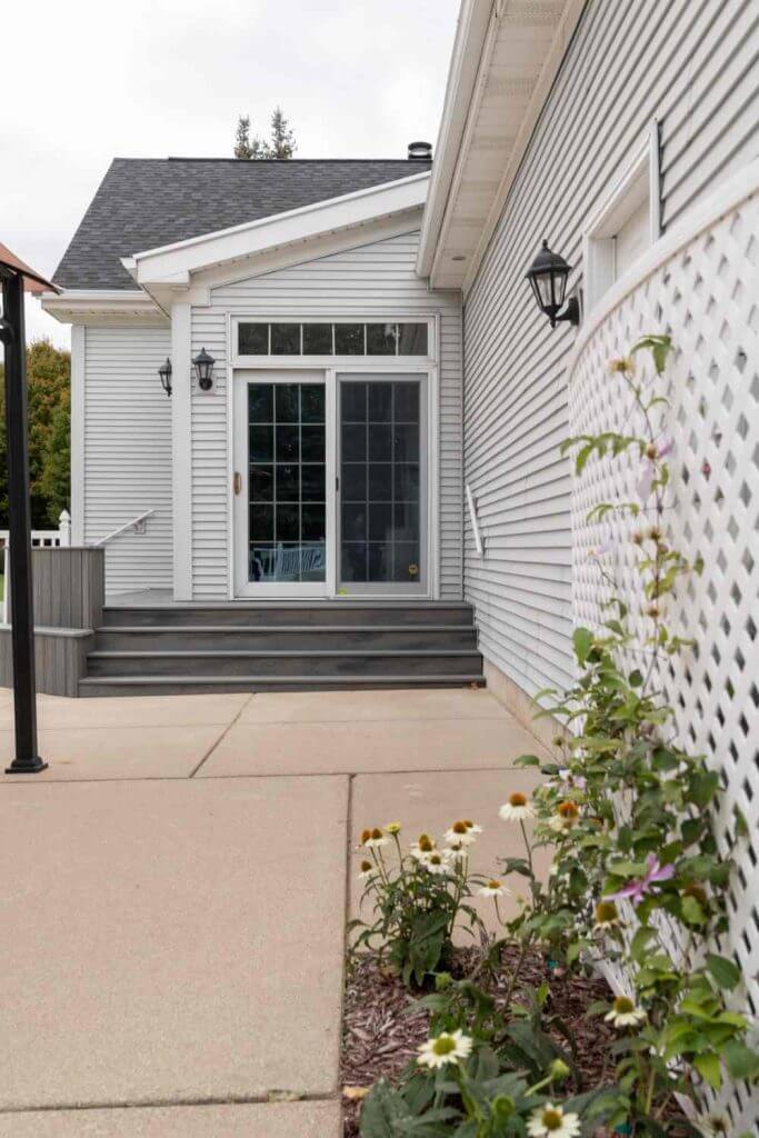 Side view of composite deck stairs and patio area installed by Odd Fellows Contracting in Williamston Michigan