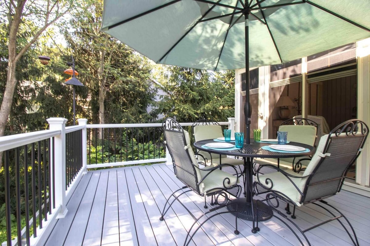 backyard deck remodel featuring patio table seating and umbrella by Odd Fellows Contracting in Williamston MI