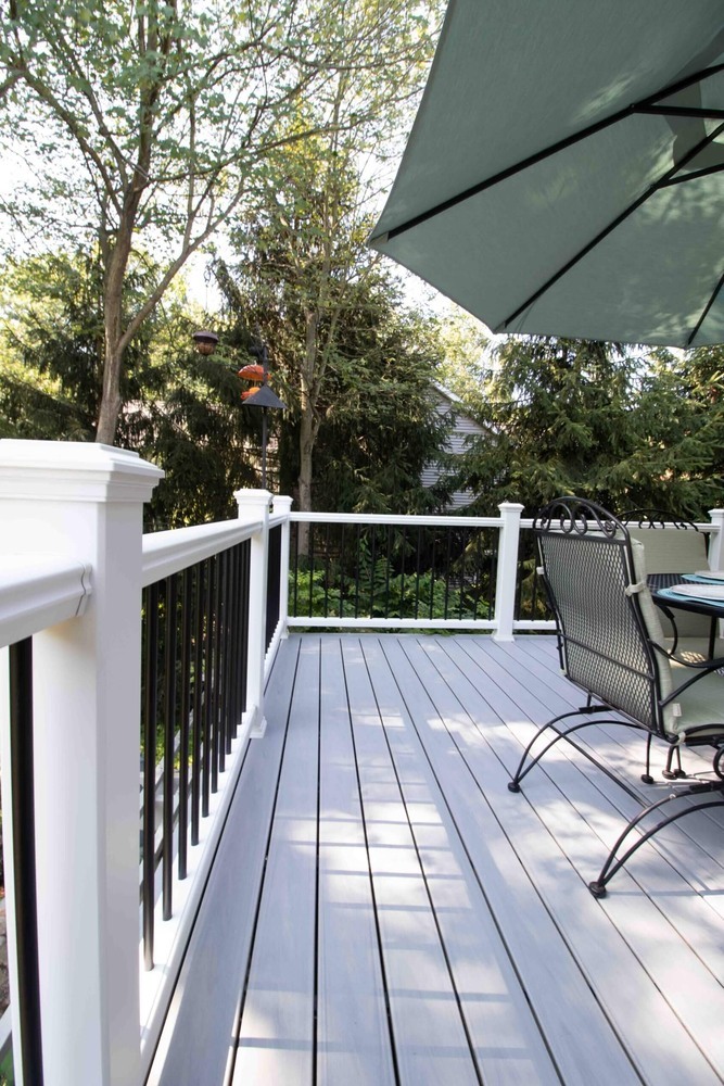 composite deck remodel with black railing balusters and outdoor dining set by Odd Fellows Contracting in Williamston MI