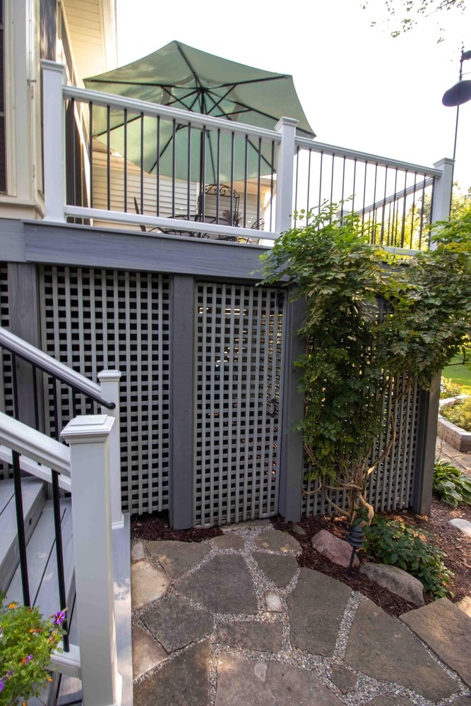composite deck staircase with white posts and black metal railings by Odd Fellows Contracting in Williamston MI