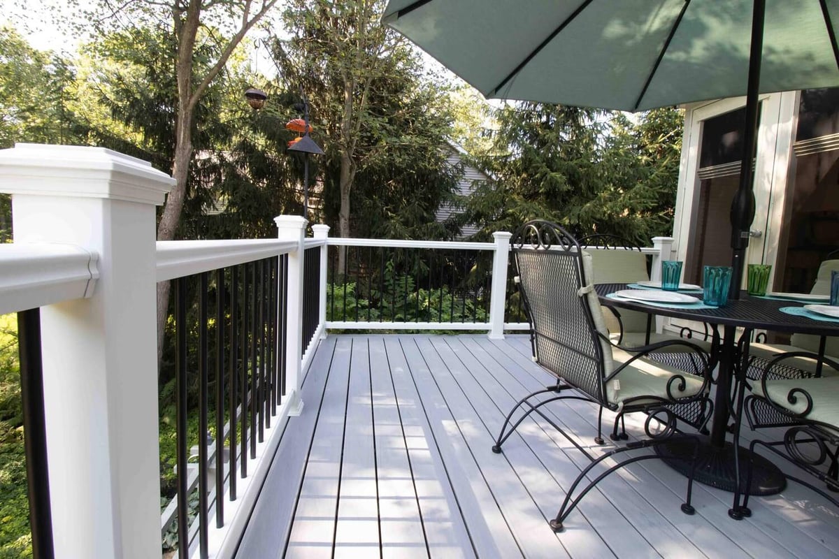 remodeled composite deck with white railing and black metal balusters by Odd Fellows Contracting in Williamston MI