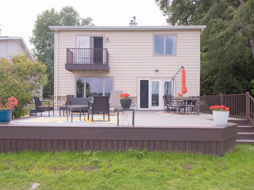 remodeled backyard deck overlooking lake with outdoor furniture and composite decking by Odd Fellows Contracting in Haslett Lake MI