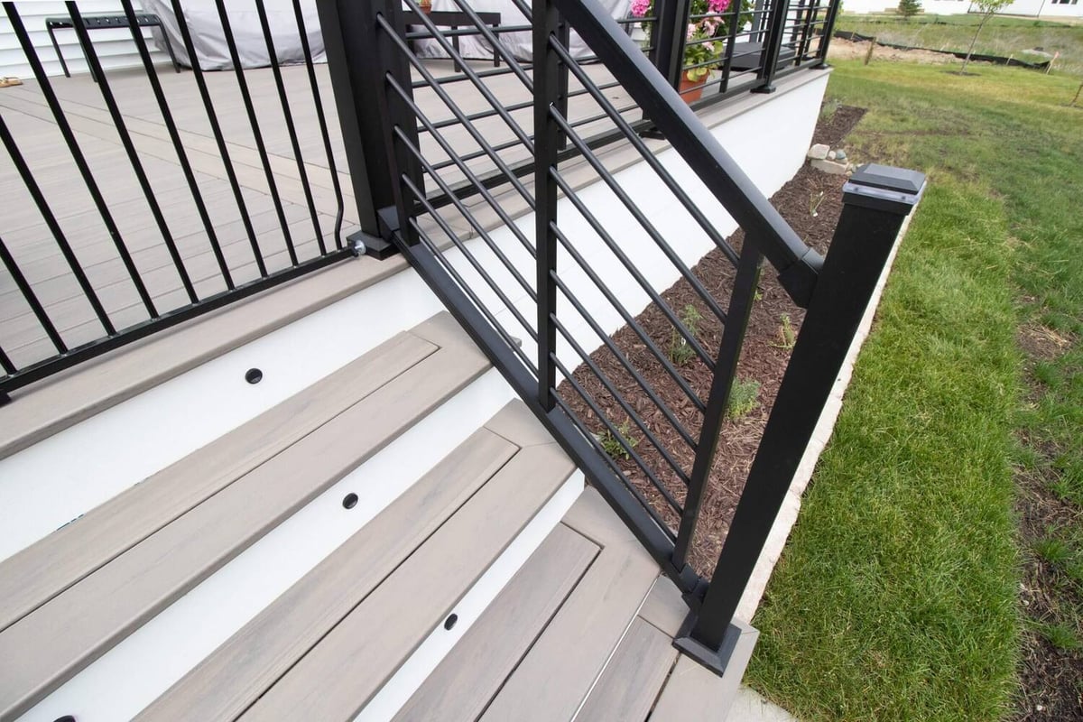 close up of deck renovation stairs with black metal railing by Odd Fellows Contracting in Haslett MI