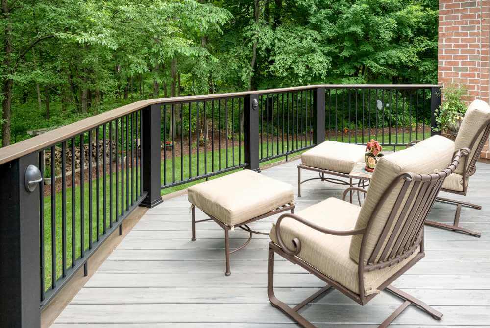 Deck seating area with composite flooring and metal railing in Williamston MI by Odd Fellows Contracting