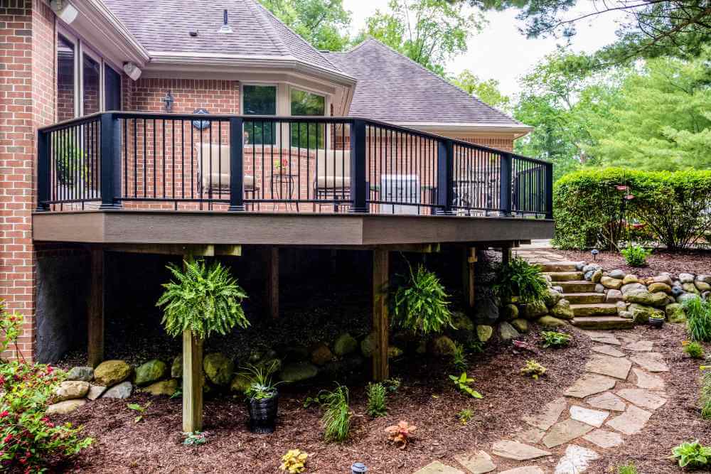 Elevated outdoor deck with railing and garden landscaping in Williamston MI remodel by Odd Fellows Contracting
