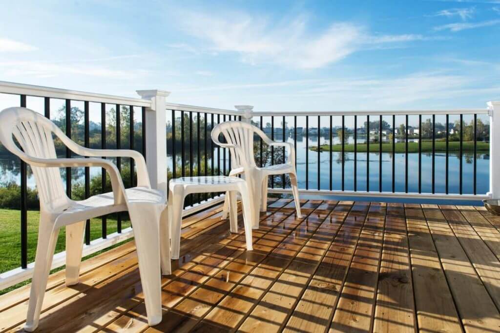 Deck seating area with white railing overlooking lake in Mason MI by Odd Fellows Contracting